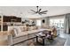 Open-concept living room featuring a large sectional sofa, modern ceiling fan, and an adjacent kitchen area at 7114 Fern Garden Ct, Sun City Center, FL 33573