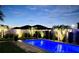 Beautifully lit backyard pool featuring sleek landscaping and modern privacy fence at 7114 Fern Garden Ct, Sun City Center, FL 33573