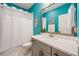 Bright bathroom with a white shower curtain, gray vanity with light countertop, and vibrant teal wall at 790 36Th N Ave, St Petersburg, FL 33704