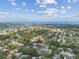 Vibrant aerial view of homes surrounded by trees, a lake, and the distant Gulf of Mexico beneath a blue, cloudy sky at 854 Village Way, Palm Harbor, FL 34683