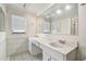Bright bathroom featuring a large mirror, dual sinks, and white tile flooring at 854 Village Way, Palm Harbor, FL 34683