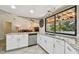 Bright kitchen features white cabinets, stainless steel appliances, and a large window overlooking the pool area at 854 Village Way, Palm Harbor, FL 34683