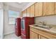Laundry room with bright red washer and dryer, upper cabinets, a sink, and a window at 854 Village Way, Palm Harbor, FL 34683