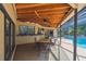Covered outdoor dining area with pool view, outdoor bar and ceiling fans at 854 Village Way, Palm Harbor, FL 34683