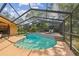 Swimming pool with lounge chairs, outdoor bar, stone waterfall feature, and a screened enclosure at 854 Village Way, Palm Harbor, FL 34683