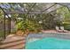 A screened pool with waterfall feature and two lounge chairs offers a relaxing outdoor retreat at 854 Village Way, Palm Harbor, FL 34683