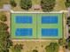 Aerial view of four community tennis courts with green and blue surfaces, surrounded by lush trees and landscaping at 854 Village Way, Palm Harbor, FL 34683