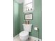 A charming powder room features soft green paneled walls, creating a serene backdrop for the classic white fixtures at 904 Villa Venicia Way, Tampa, FL 33606