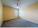 Bright bedroom featuring a ceiling fan, a window with blinds for natural light, and neutral-colored walls and carpet at 9324 Rally Spring Loop, Wesley Chapel, FL 33545