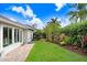 Well-maintained backyard with green lawn, patio, and side yard featuring colorful tropical landscaping at 10231 Millport Dr, Tampa, FL 33626