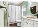 Bathroom featuring an oval sink, white cabinetry, and tropical wallpaper with a dark wood-look floor at 10231 Millport Dr, Tampa, FL 33626