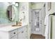 Bathroom featuring an oval sink, white cabinetry, and tropical wallpaper with a dark wood-look floor at 10231 Millport Dr, Tampa, FL 33626