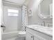 Bright, neutral bathroom with a white vanity, updated fixtures, tile floor, and shower with patterned curtain at 10231 Millport Dr, Tampa, FL 33626