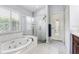 Bright bathroom showcasing a jacuzzi tub and frameless glass shower with white tiling and neutral paint at 10231 Millport Dr, Tampa, FL 33626