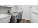 Laundry room with front load washer/dryer, utility sink, shelving and hooks, and wood-look flooring at 10231 Millport Dr, Tampa, FL 33626