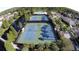Aerial view of community tennis courts adjacent to a pool and pond surrounded by lush landscaping and residences at 10231 Millport Dr, Tampa, FL 33626