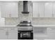 Contemporary kitchen features stainless steel appliances, white cabinetry, tile backsplash, and modern range hood at 10701 Glen Ivy Ln, Tampa, FL 33624