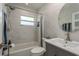 Bright bathroom featuring a modern vanity, tub/shower combo with tiled surround, and a round mirror at 1250 S Pinellas Ave # 214, Tarpon Springs, FL 34689