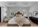 Spacious main bedroom featuring wood floors, tray ceiling, plantation shutters, and an accent chair at 12705 Green Heron Way, Odessa, FL 33556
