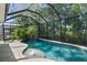 Screened-in pool featuring waterfall, lush landscaping, and an in-ground spa at 12705 Green Heron Way, Odessa, FL 33556