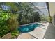 Wide view of the screened-in pool with stone surround, waterfall, spa, and landscaping at 12705 Green Heron Way, Odessa, FL 33556