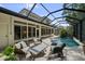 Screened-in pool area surrounded by patio furniture, featuring a waterfall and lush landscaping at 12705 Green Heron Way, Odessa, FL 33556