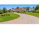Elegant Mediterranean-style home features lush landscaping, a tile roof, and brick-paved circular driveway at 17124 Crawley Rd, Odessa, FL 33556