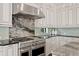 Close up on stovetop, granite counters, with custom white cabinets, and light backsplash in the kitchen at 17124 Crawley Rd, Odessa, FL 33556