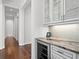 Elegant wine bar area with marble countertops, glass shelving, and a built-in wine cooler enhances entertaining at 17124 Crawley Rd, Odessa, FL 33556
