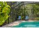 Relaxing poolside chairs in screened-in pool area, surrounded by lush landscaping and serene privacy at 17318 Emerald Chase Dr, Tampa, FL 33647