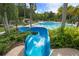 View of the refreshing community pool and slide surrounded by tropical landscaping and lush foliage at 17318 Emerald Chase Dr, Tampa, FL 33647