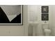 Small bathroom features a pedestal sink, toilet, decorative art, and minimalist finishes at 18461 Serene Lake Loop, Lutz, FL 33548