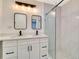 Modern bathroom featuring double sinks, framed mirrors, vanity lighting, glass shower, and white cabinetry at 1914 E Emma St, Tampa, FL 33610
