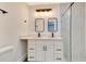 Modern bathroom with dual sinks, framed mirrors, vanity lighting, glass-enclosed shower, and white cabinets at 1914 E Emma St, Tampa, FL 33610