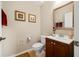 Cozy half bathroom with wood vanity, decorative mirror, neutral walls and tan colored tile floors at 20039 Heritage Point Dr, Tampa, FL 33647