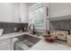 Close-up of a kitchen sink with white cabinets, gray backsplash, and plantation shutters at 209 S Arrawana Ave, Tampa, FL 33609