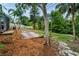 Backyard featuring a paver area, wood mulch, and various trees and vegetation, offering privacy and shade at 2485 Indigo Dr, Clearwater, FL 33763