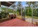 Backyard featuring a red wooden deck, brick fireplace, and screened enclosure amongst the lush landscaping at 2485 Indigo Dr, Clearwater, FL 33763