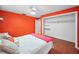 A bright bedroom with red walls, hardwood floors, a cozy bed setup, and a large closet at 2485 Indigo Dr, Clearwater, FL 33763
