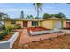 Charming yellow single-story home with a red door, well-manicured landscaping and an attached garage at 2485 Indigo Dr, Clearwater, FL 33763
