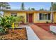 Bright yellow home with a red door, white trim, and well-manicured landscaping at 2485 Indigo Dr, Clearwater, FL 33763
