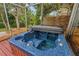 Close-up of a blue hot tub with a wooden surround, located on a screened deck, surrounded by lush greenery at 2485 Indigo Dr, Clearwater, FL 33763