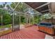 Enclosed deck with a hot tub, red wooden flooring, and view of the yard with lush greenery at 2485 Indigo Dr, Clearwater, FL 33763