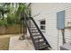 Exterior back view of home with black metal stairway and lawn at 2814 W Humphrey St, Tampa, FL 33614