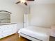 Bright bedroom with hardwood floors, ceiling fan, white walls, closet, and a white dresser with a large mirror at 3001 Regal Oaks Blvd, Palm Harbor, FL 34684