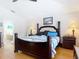 Well-lit bedroom featuring a four-poster bed, hardwood floors, and a view into the bathroom at 3001 Regal Oaks Blvd, Palm Harbor, FL 34684