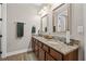 Elegant bathroom with dual sinks, granite counters, wood cabinets, mirrors, lighting, and hardwood floors at 32122 Wenlock Loop, Wesley Chapel, FL 33543