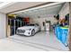 Well-organized three-car garage with epoxy flooring, cabinets, and an electric car at 32122 Wenlock Loop, Wesley Chapel, FL 33543