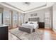 Serene main bedroom with tray ceilings, wood floors, a tufted headboard, and abundant natural light at 32122 Wenlock Loop, Wesley Chapel, FL 33543