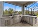 Outdoor kitchen featuring modern stainless steel appliances, stone countertops, and a comfortable bar area at 32122 Wenlock Loop, Wesley Chapel, FL 33543